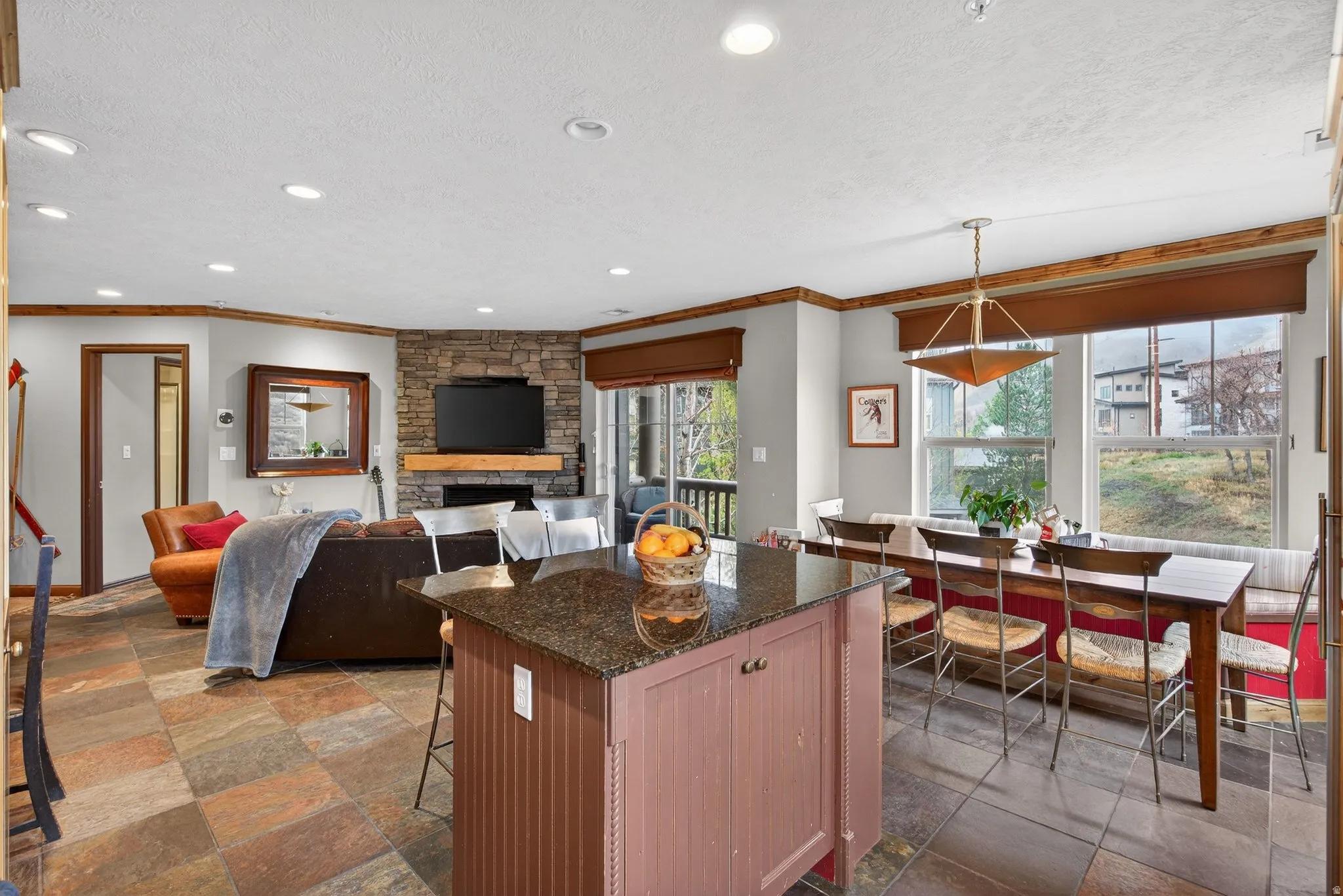 Kitchen with stone tile floors, dark stone countertops, a kitchen bar, a textured ceiling, and a kitchen island
