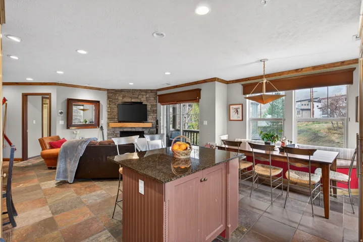 Kitchen with stone tile floors, dark stone countertops, a kitchen bar, a textured ceiling, and a kitchen island
