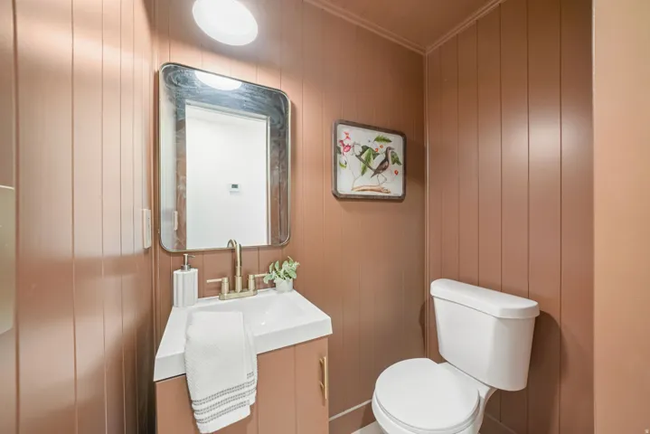 Bathroom with vanity, ornamental molding, and wooden walls