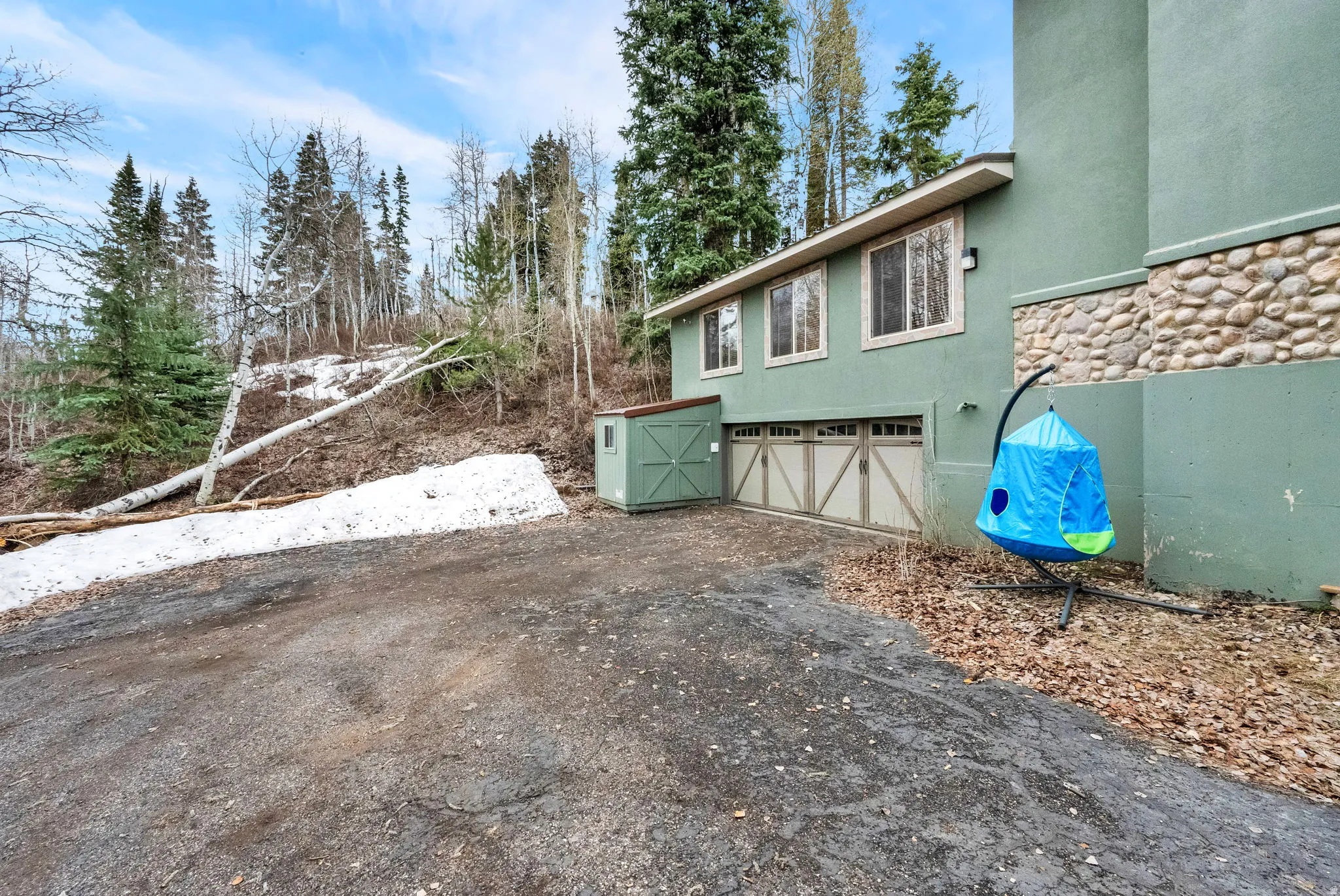View of side of property with an attached garage, stucco siding, and asphalt driveway