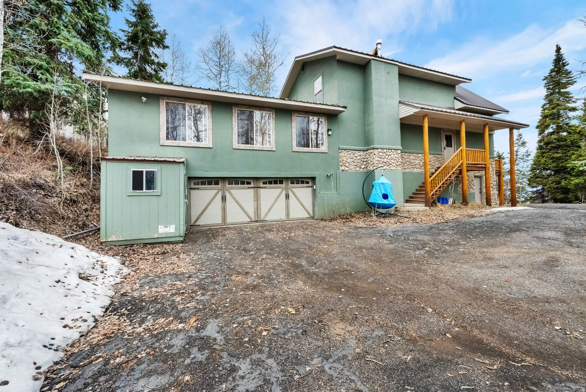View of front facade with an attached garage, driveway, a metal roof, stucco siding, and stone siding