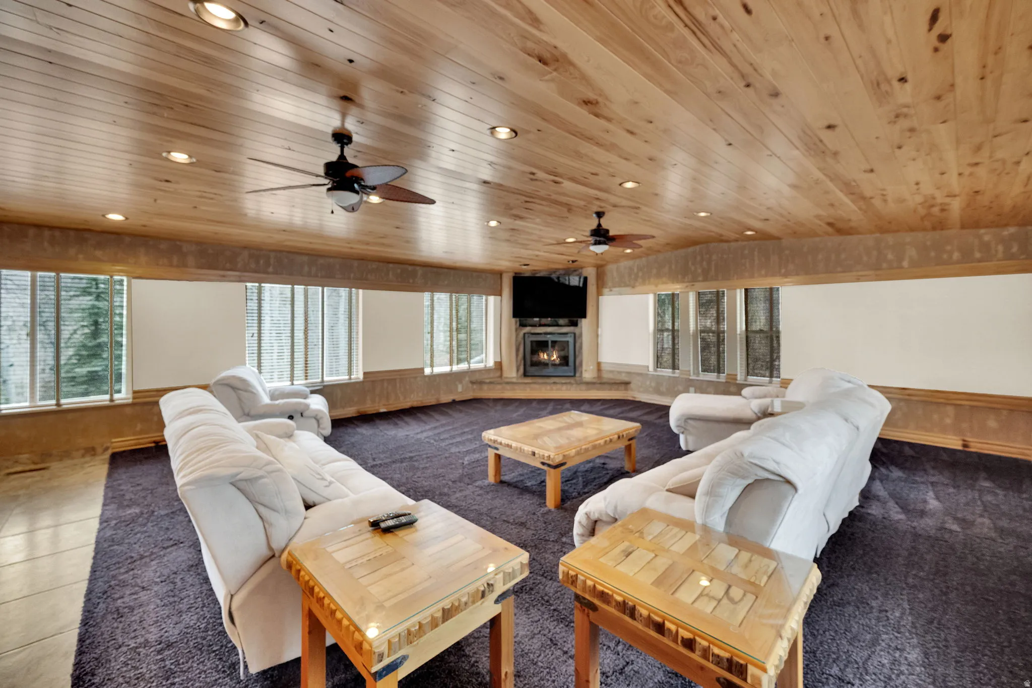 Living room featuring a glass covered fireplace, recessed lighting, carpet flooring, wood ceiling, and a ceiling fan