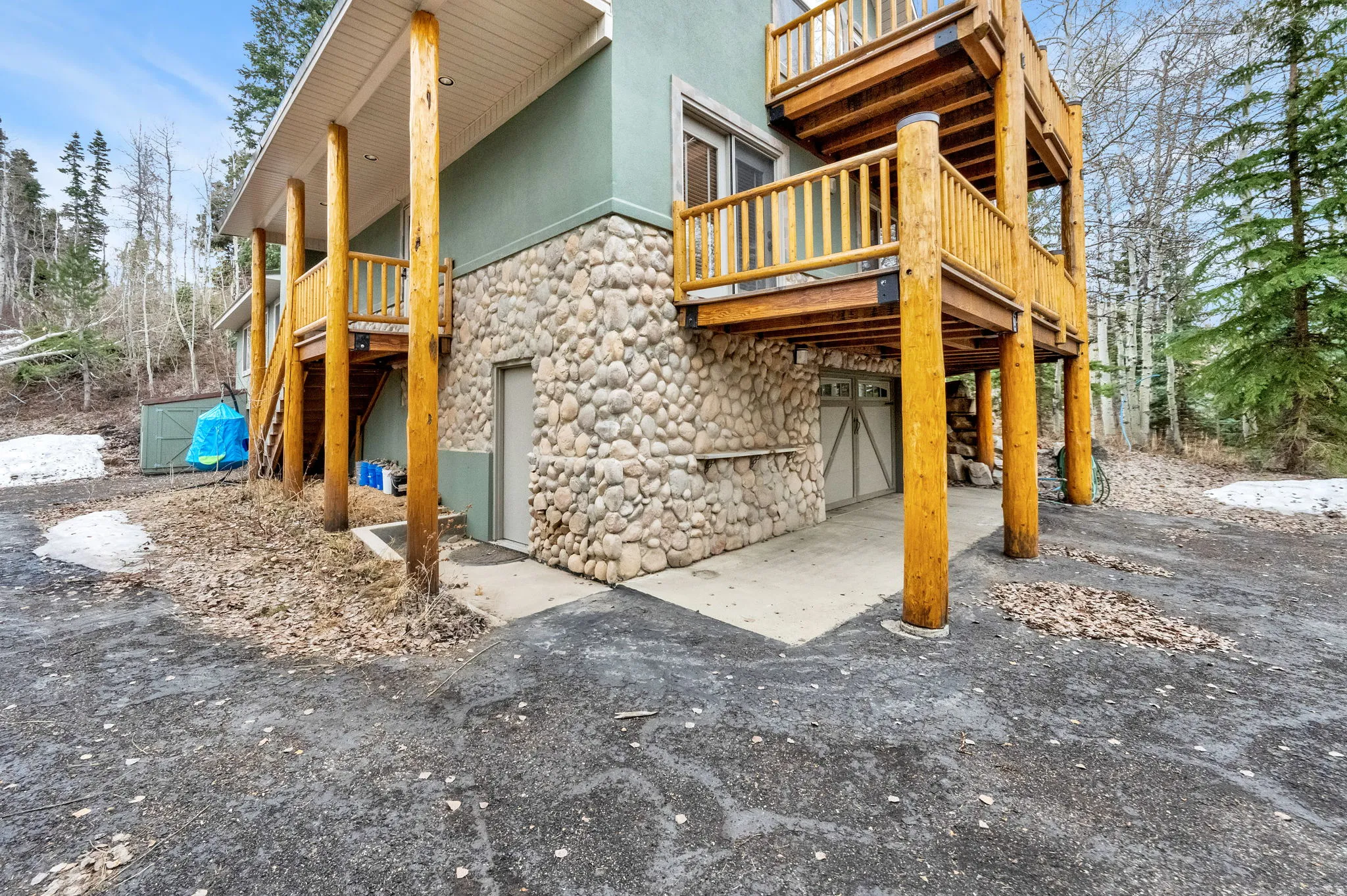 Exterior space featuring stone siding, an attached garage, and a deck