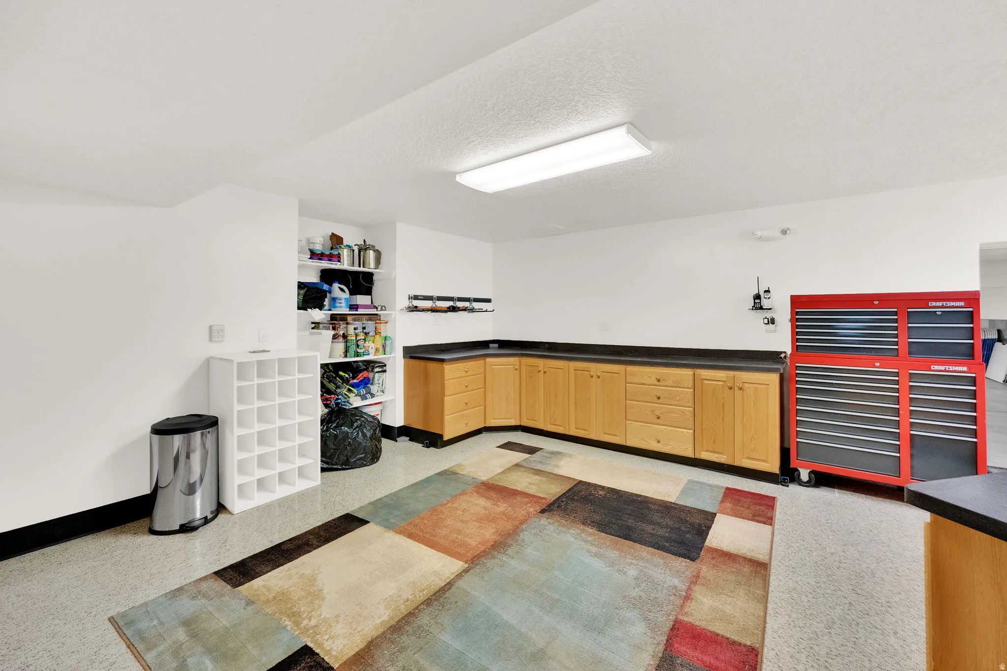 Kitchen with light wood finish cabinets, dark countertops, a textured ceiling, and light floors