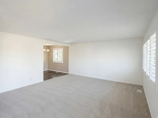 Unfurnished room featuring dark colored carpet and hanging lights
