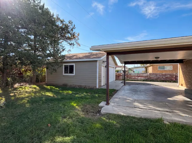 View of side of property with an outdoor structure, a patio, a garage, and a carport
