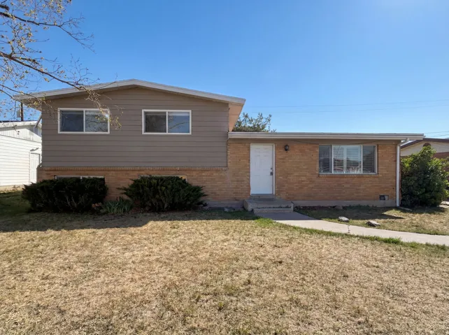 Tri-level home with brick siding and a front yard