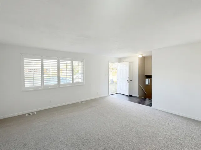 Empty room featuring dark colored carpet and baseboards