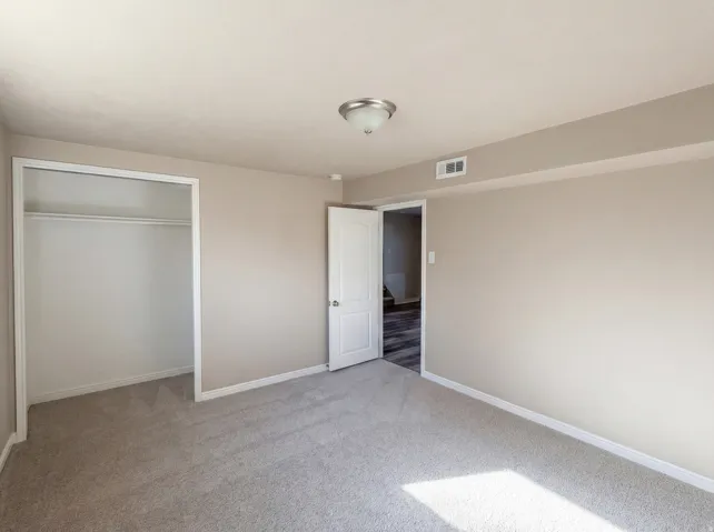 Unfurnished bedroom with light carpet and a closet