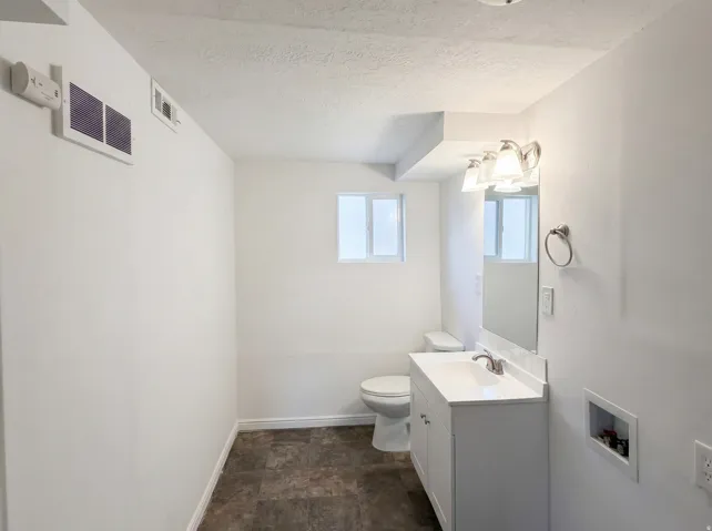 Bathroom featuring vanity, a textured ceiling, and stone finish flooring