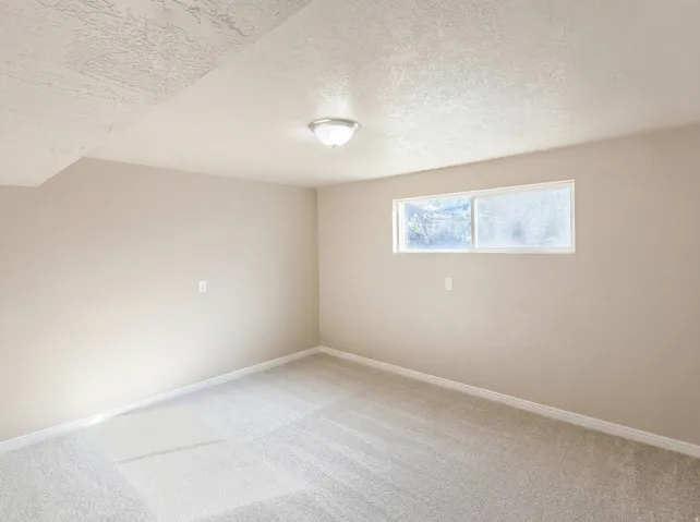 Empty room featuring light colored carpet and a textured ceiling
