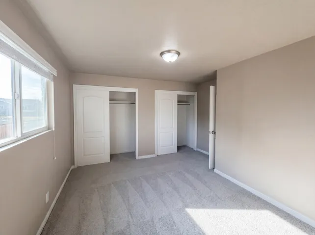 Unfurnished bedroom featuring multiple closets and light carpet