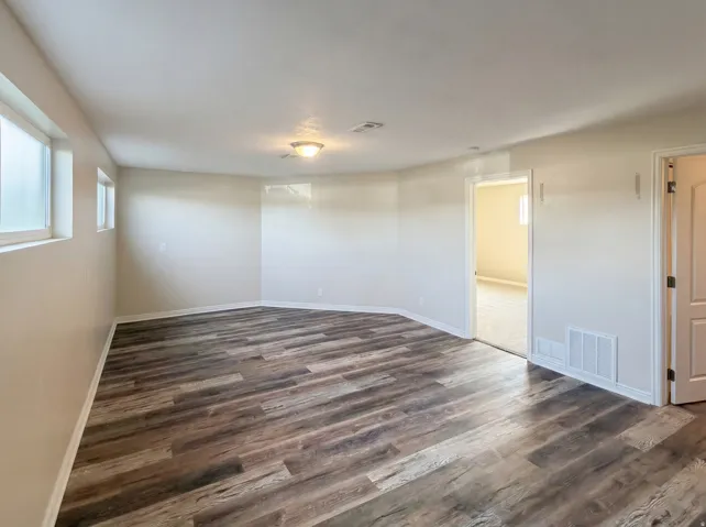 Spare room featuring dark wood finished floors and baseboards