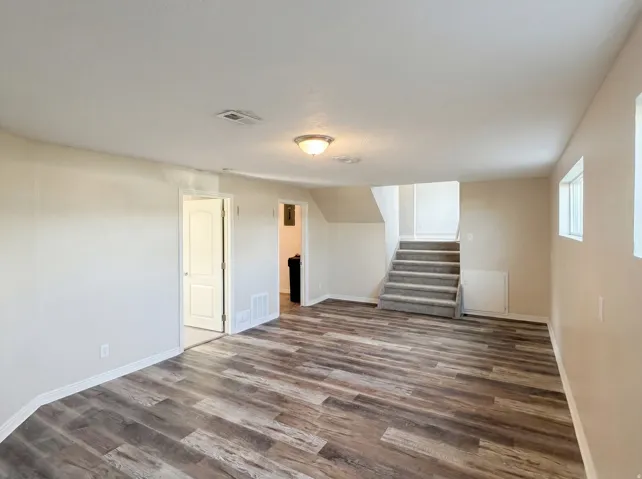 Spare room with stairway and dark wood-style floors