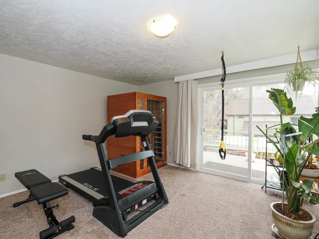 Exercise area featuring light colored carpet and a textured ceiling