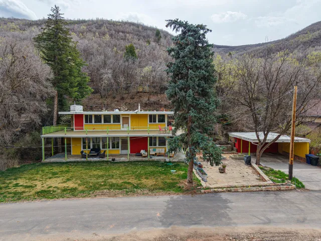 View of front of property featuring a forest view, a front lawn, a mountain view, driveway, and a porch