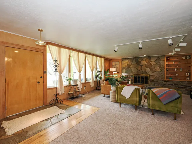 Carpeted living room featuring a textured ceiling, track lighting, and a fireplace