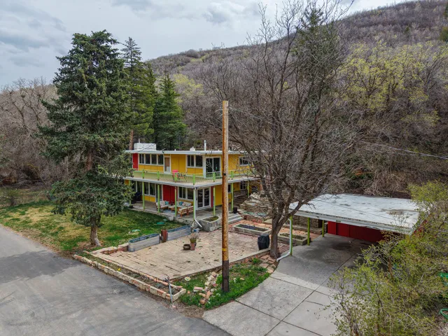View of front of house featuring a carport, a porch, a front lawn, a view of trees, and concrete driveway