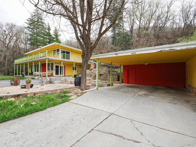 View of front of home with concrete driveway, a patio area, a large porch, and an attached carport