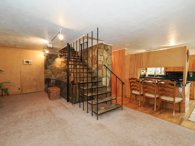 Staircase with a textured ceiling, carpet, track lighting, and wood walls