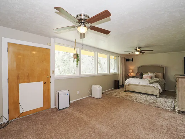 Bedroom with a textured ceiling, a ceiling fan, and carpet flooring