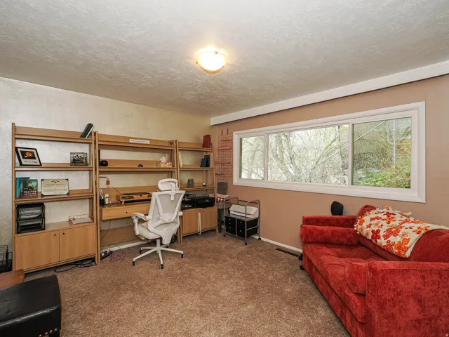 Home office with light colored carpet and a textured ceiling