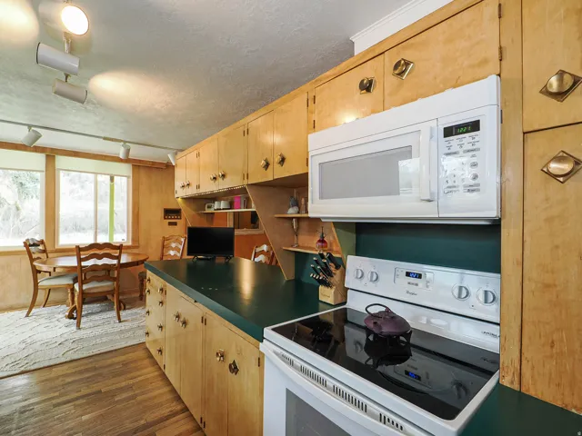 Kitchen featuring white appliances, a textured ceiling, dark wood-type flooring, dark countertops, and rail lighting