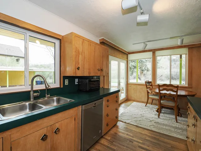 Kitchen featuring dark countertops, stainless steel dishwasher, dark wood finished floors, a textured ceiling, and rail lighting