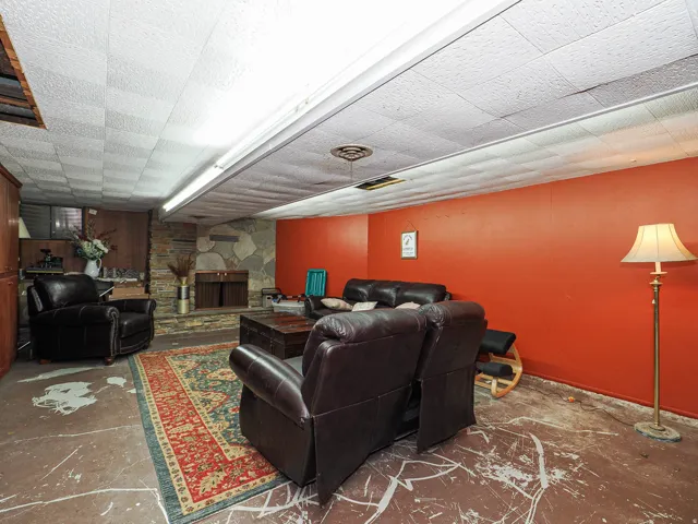 Living area featuring a stone fireplace and concrete flooring