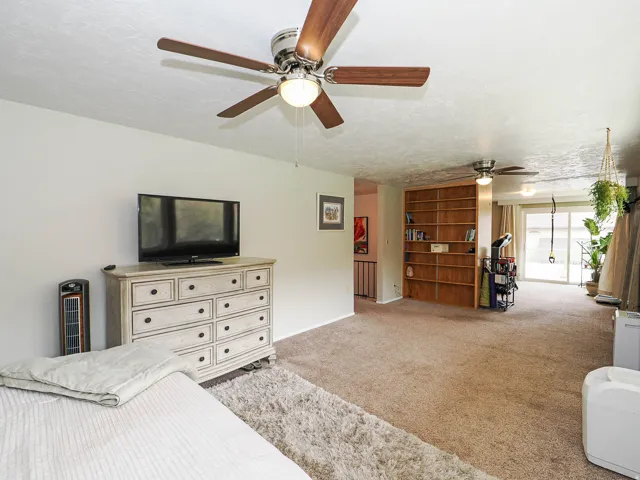 Bedroom with a textured ceiling, light carpet, and ceiling fan