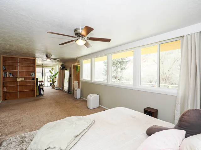 Bedroom with carpet floors, a textured ceiling, and a ceiling fan