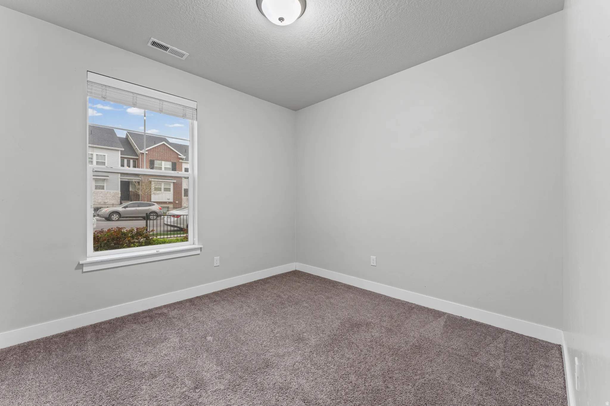 Spare room with dark carpet and a textured ceiling