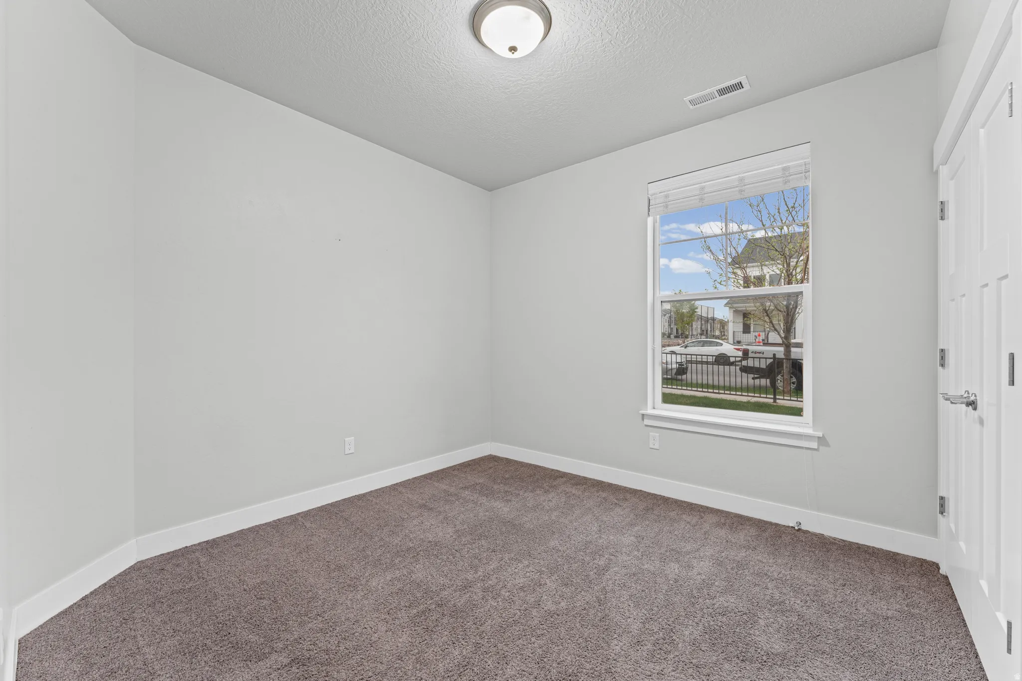 Unfurnished bedroom with dark colored carpet and a textured ceiling