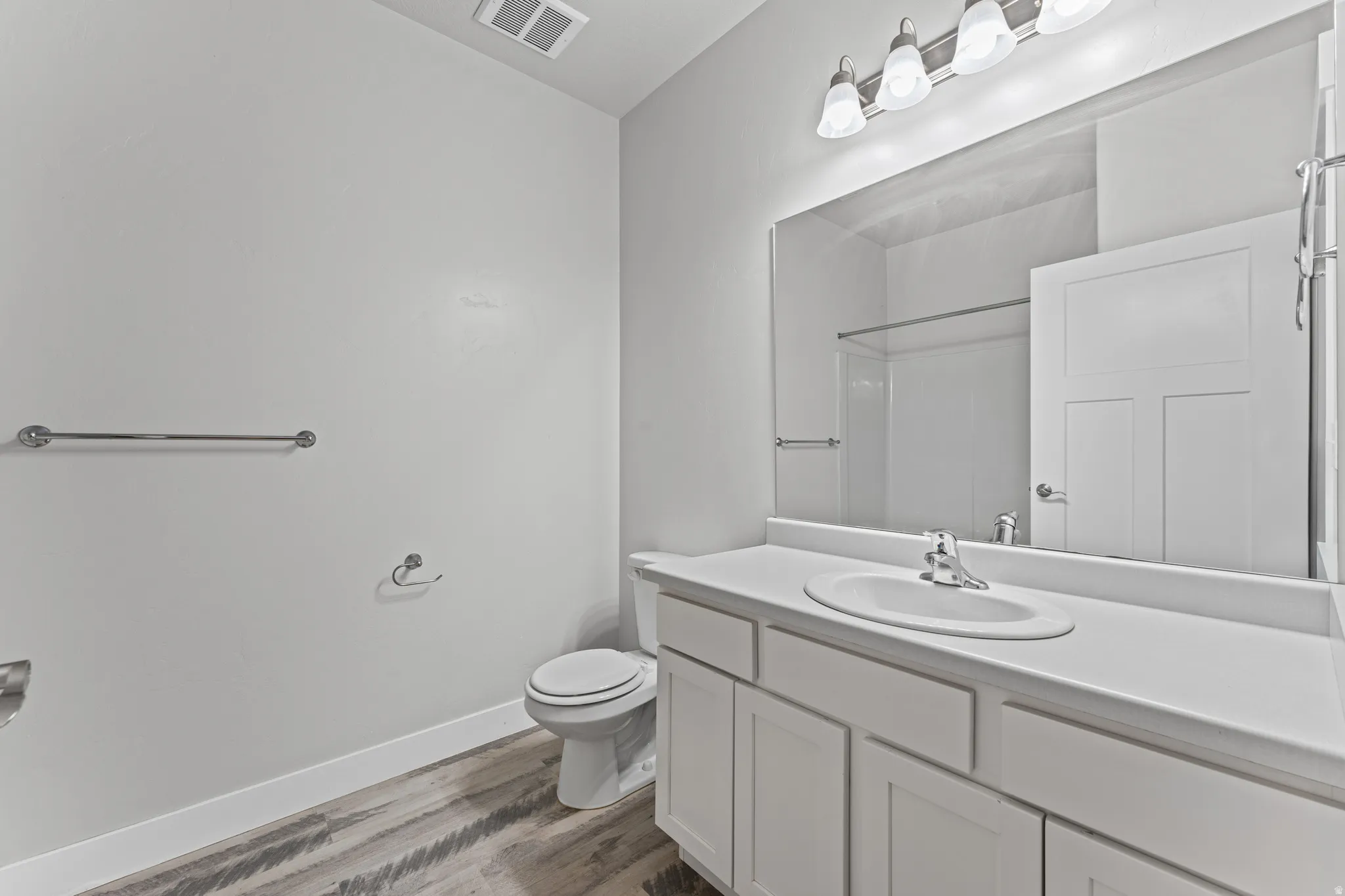 Bathroom with vanity, dark wood-style flooring, and a shower