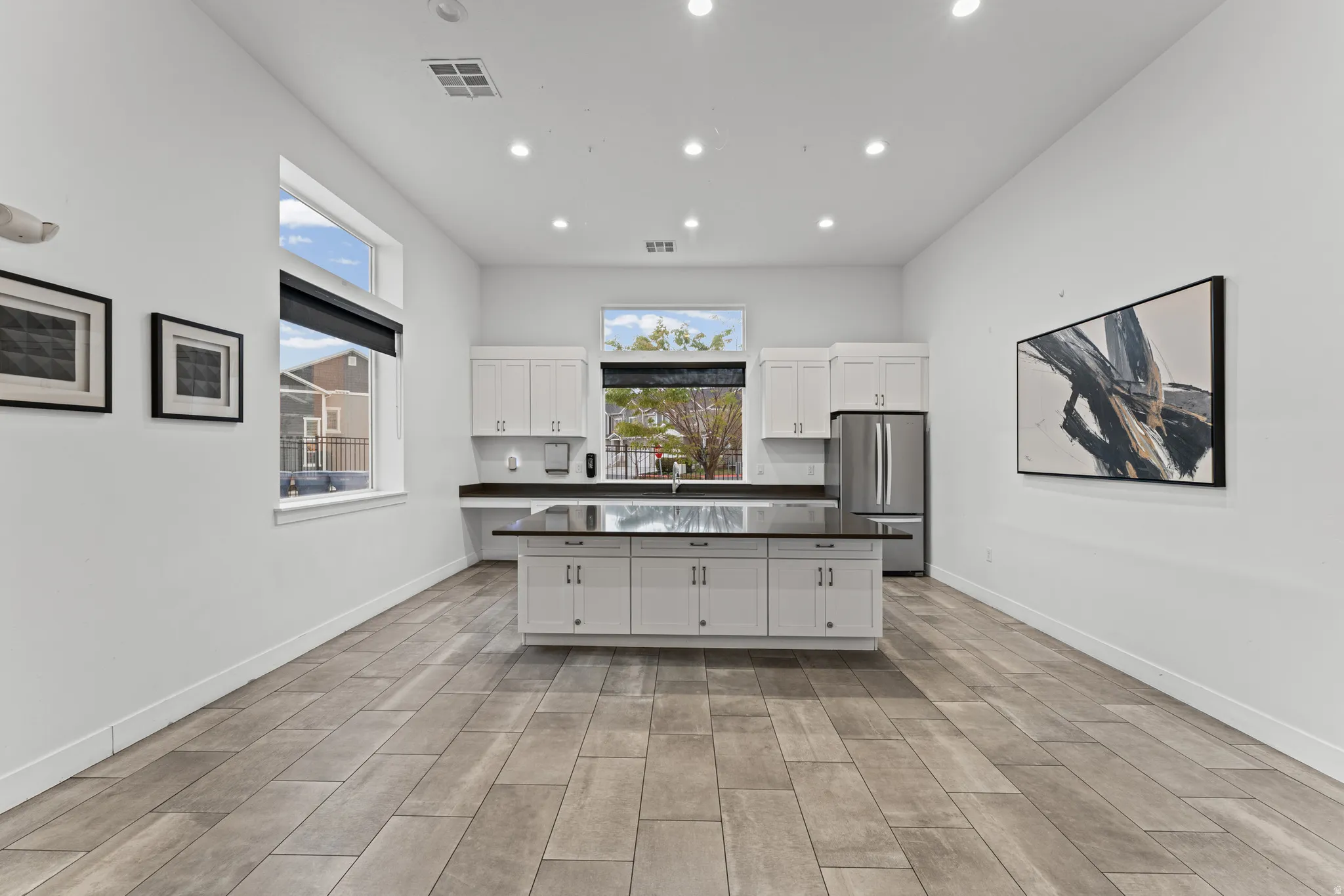 Kitchen featuring white cabinets, a center island, freestanding refrigerator, dark countertops, and wood finish floors