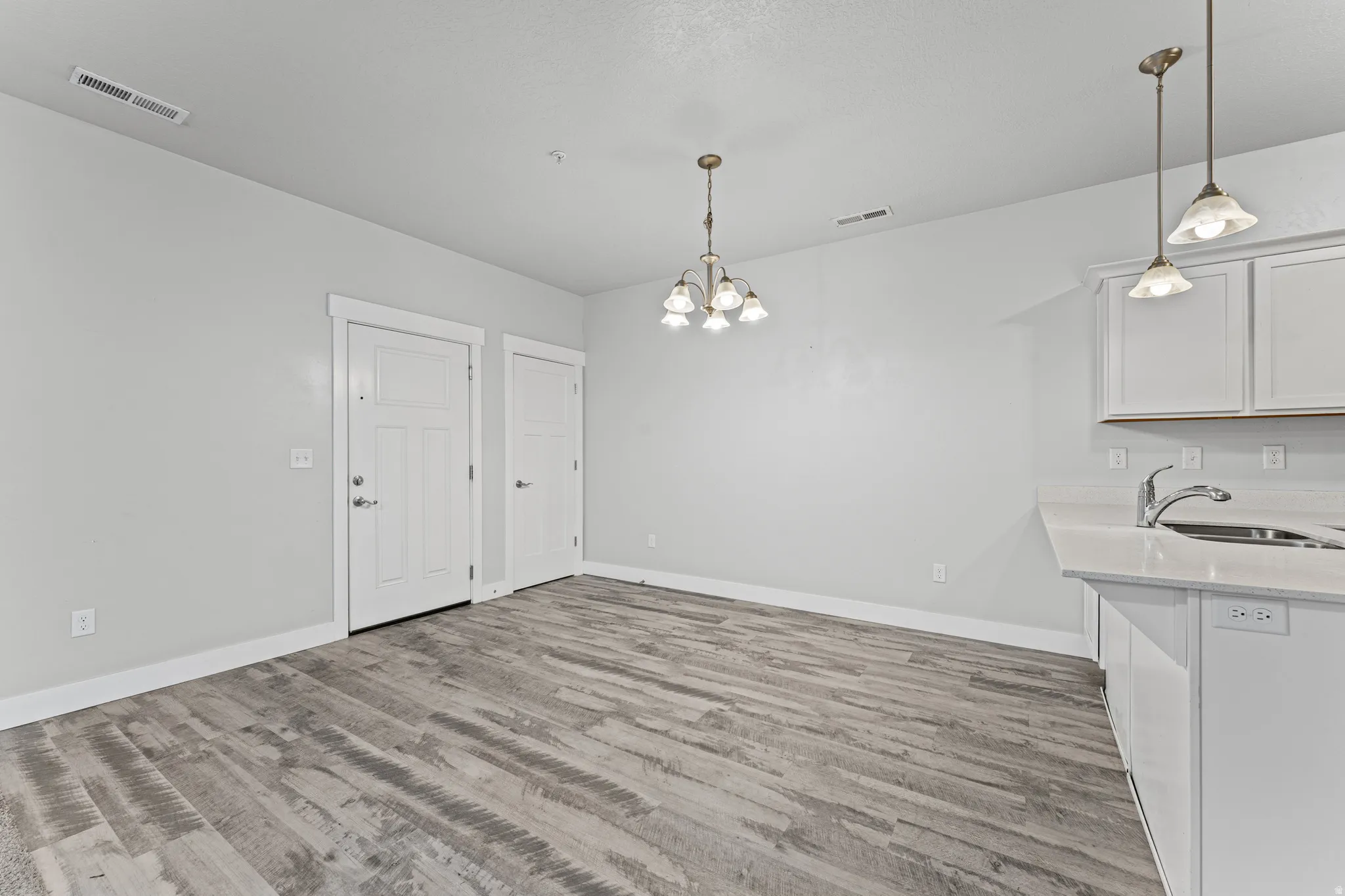 Unfurnished dining area with suspended lighting and light wood-style flooring