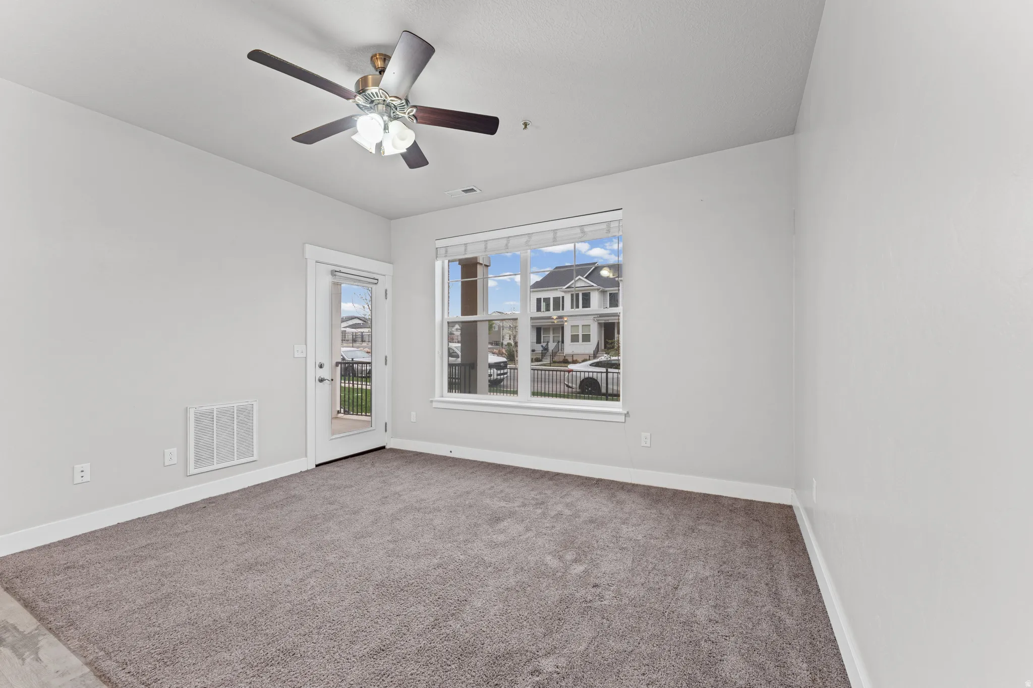 Carpeted spare room with baseboards and ceiling fan