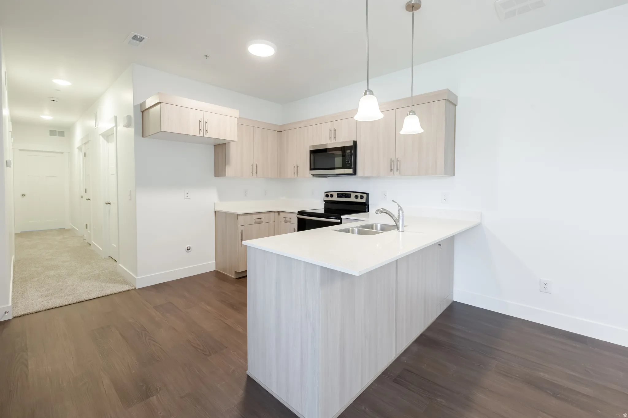 Modern kitchen featuring wood-finish cabinetry, stainless steel appliances, and a central island with a sink