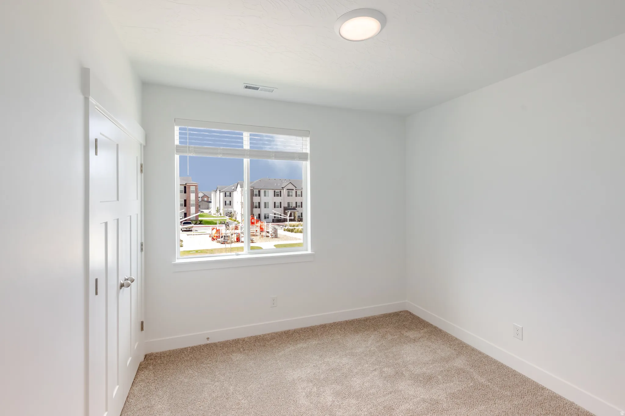 Neutral wall finishes, carpeted flooring, a recessed ceiling light, and a window with blinds