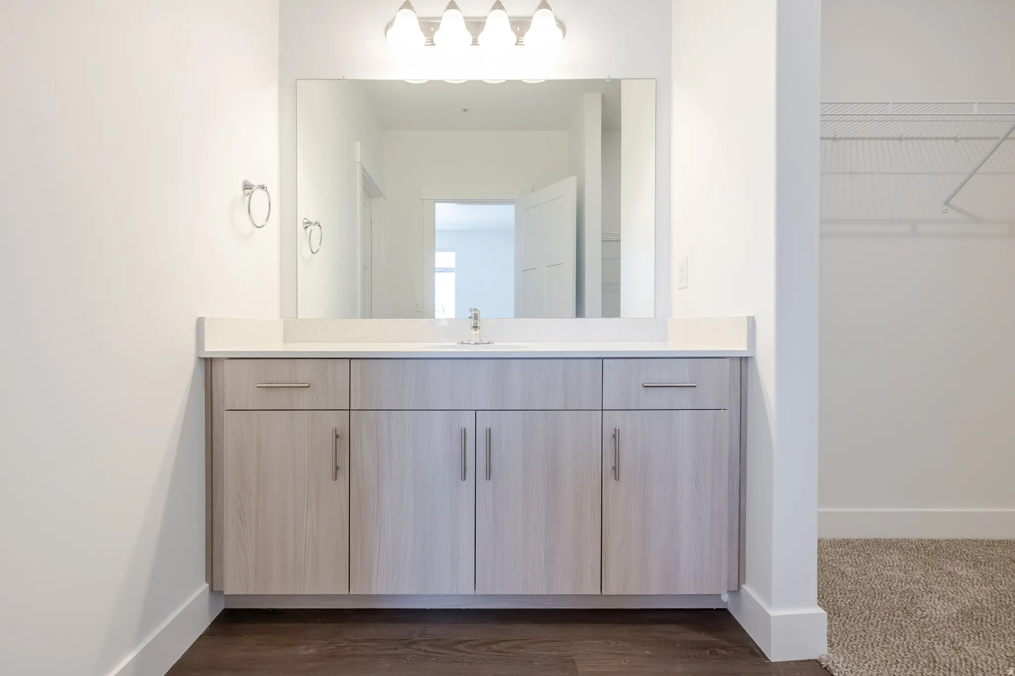 Floating vanity with wood-finish cabinetry, light-toned countertop, and integrated sink