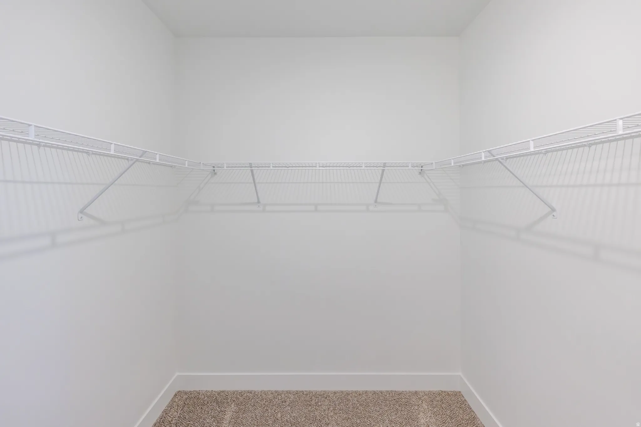 White wire shelving system, light-colored carpeting, white wall paint