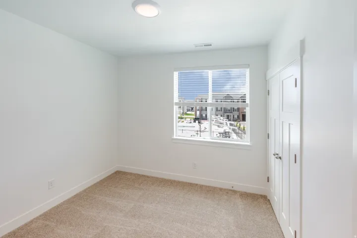 Neutral wall color, plush carpet, recessed lighting, window with blinds, and paneled closet doors