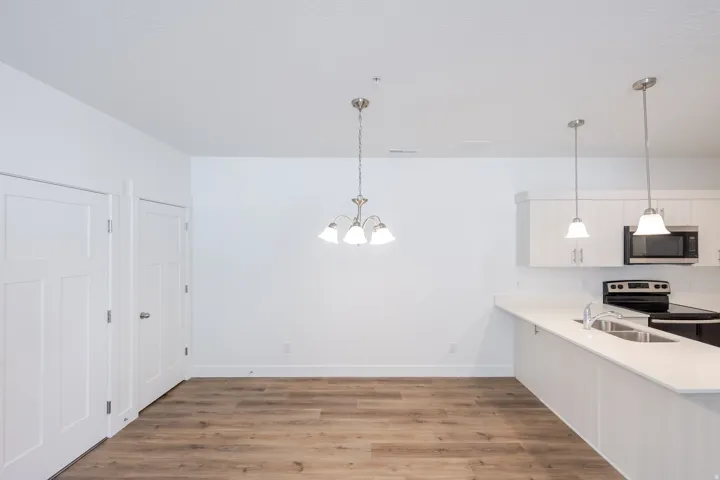 Wood-finish flooring throughout, white shaker cabinetry, stainless steel microwave, and pendant lighting