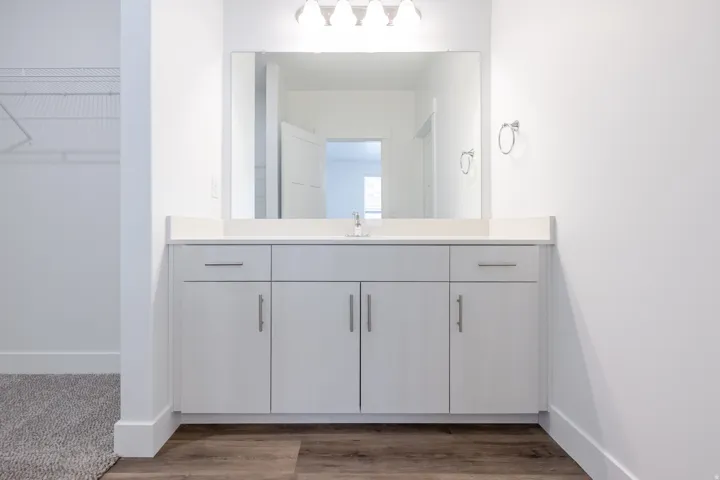 White vanity with a neutral countertop, undermount sink, and chrome fixtures