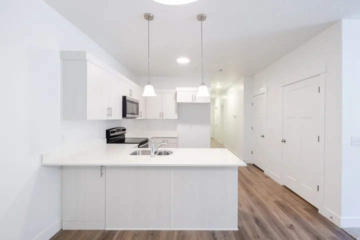 Modern kitchen featuring white cabinetry, a large kitchen island with an integrated sink, and stainless steel appliances