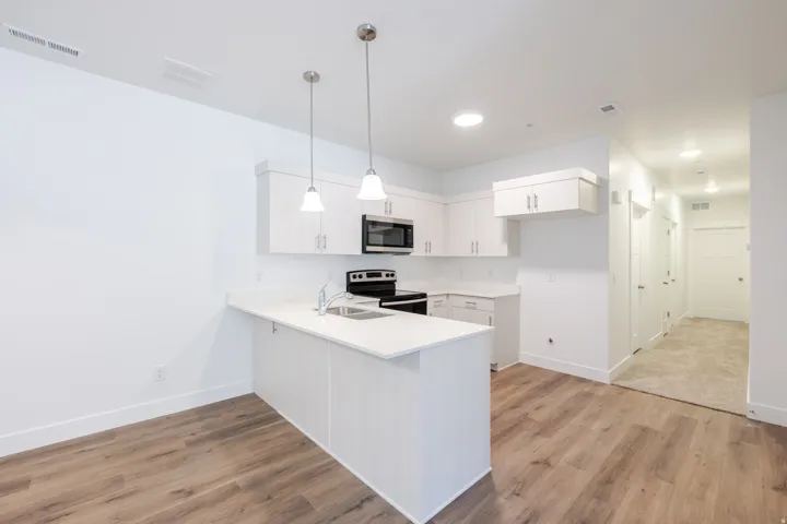 Kitchen featuring white cabinetry, stainless steel appliances, and a breakfast bar with pendant lighting