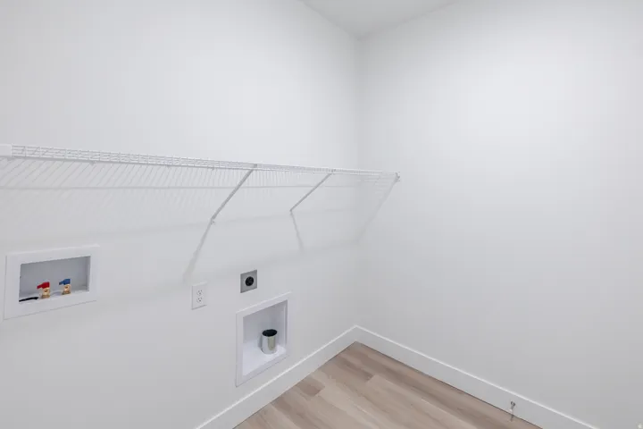 Laundry area with light wood-finish flooring and a white wire shelf