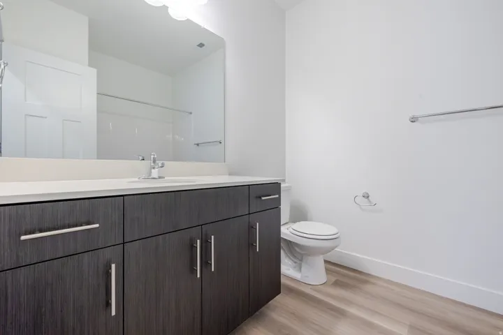 Modern bathroom featuring a vanity with dark wood-finish cabinetry, a light-toned countertop, and an integrated sink