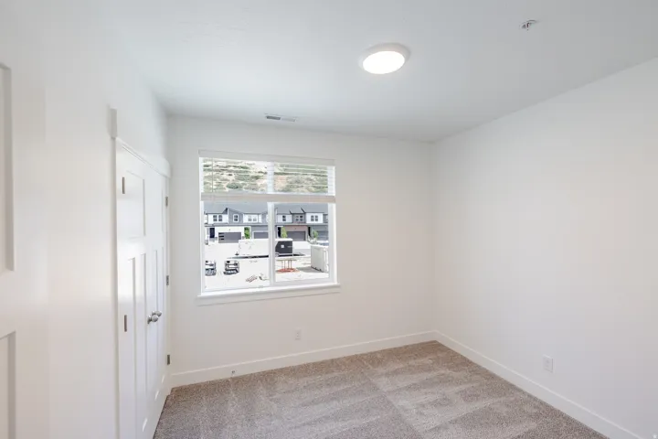 Neutral wall paint, plush carpet flooring, recessed lighting, and a multi-pane window with blinds