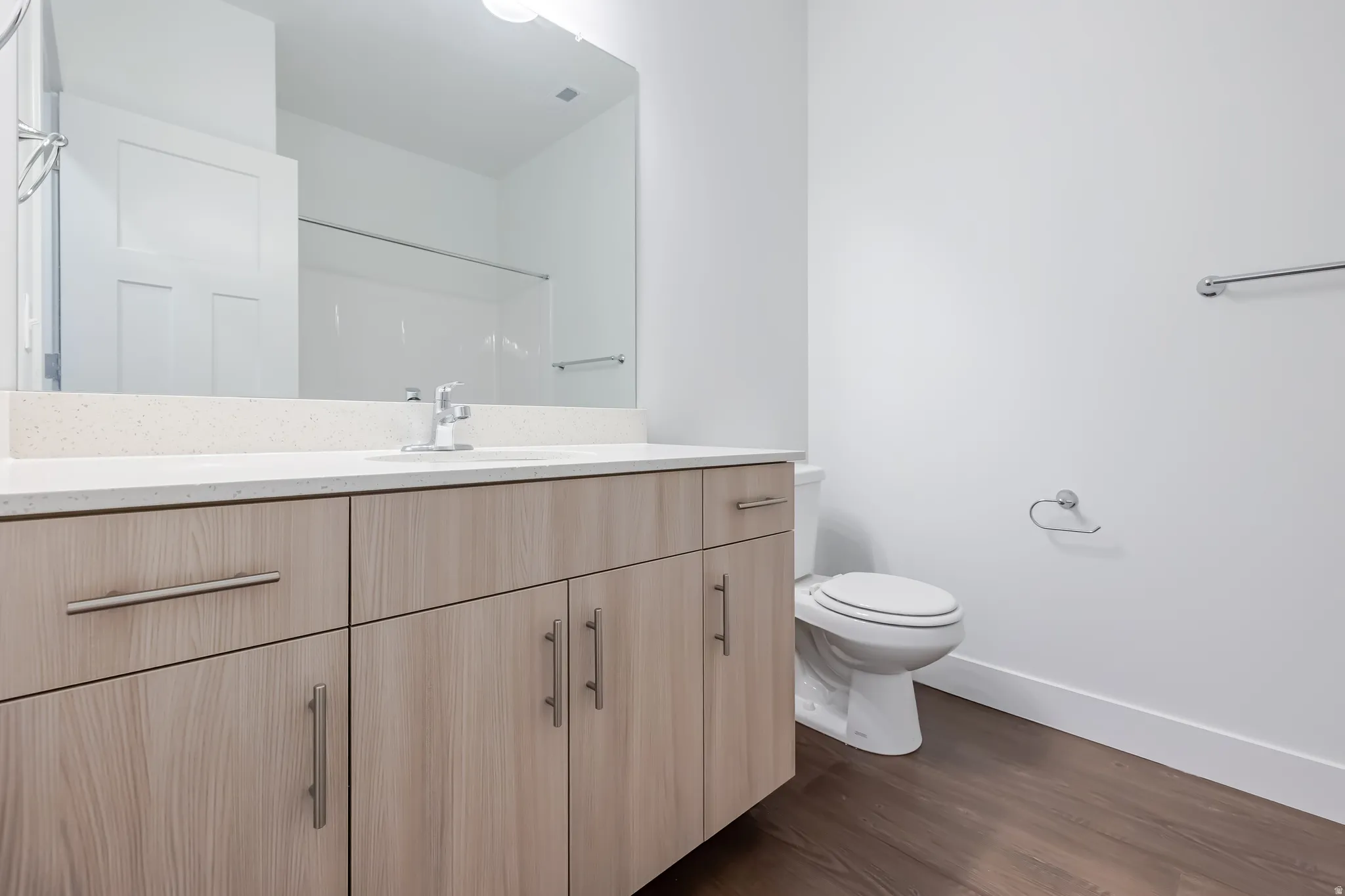 Wood-finish vanity with ample storage, a light-colored countertop, and a large wall-mounted mirror